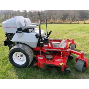May include: A red and gray zero-turn riding lawnmower with a large, gray, plastic seat and a black cup holder. The mower has a large, white, front tire and smaller, black, rear tires.