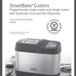 Op de afbeelding: Een zilveren en zwarte Sunbeam SmartBake Custom programmeerbare broodbakmachine en deegmaker met een digitaal display en een fruit- en noten dispenser. De broodbakmachine staat op een houten oppervlak met een mes en een pot met ingrediënten.