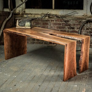 May include: A rustic wooden coffee table with a live edge design. The table has a natural wood finish and is made of two separate pieces.