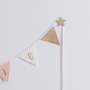 May include: A pink, white and gold glitter banner with the word "love" spelled out on it. A gold glitter star is attached to the end of the banner.