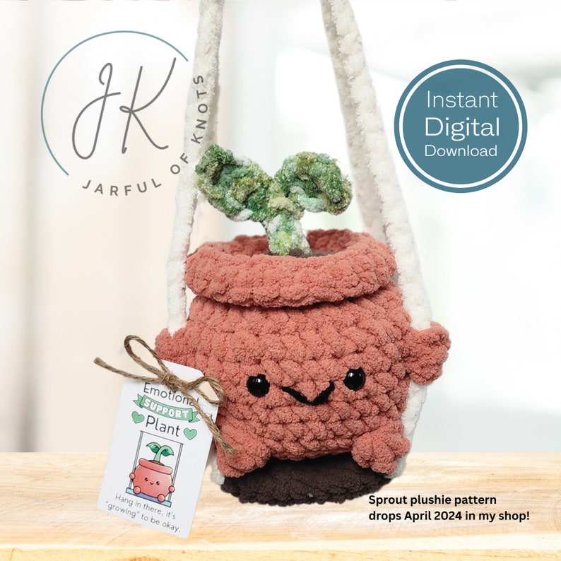 Pu&ograve; includere: Un giocattolo di peluche lavorato a uncinetto a forma di pianta in vaso con un germoglio che spunta dalla parte superiore. Il vaso ha un viso sorridente e la pianta &egrave; verde. Il giocattolo &egrave; appeso a una cinghia di uncinetto bianca. L'etichetta attaccata al giocattolo recita "Emotional Support Plant" e "Hang in there, it's 'growing' to be okay."