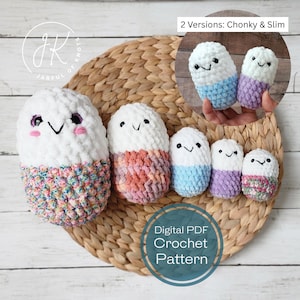 May include: A collection of handmade crochet plushies in various sizes and colors, including white, blue, pink, and purple. The plushies have smiling faces and are arranged on a woven mat. The image includes the text "Digital PDF Crochet Pattern."