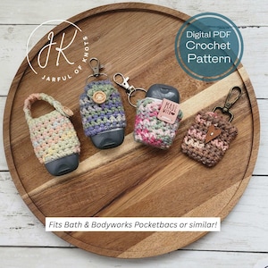 May include: Four handmade crochet pocketbac holders in various colors, including pink, green, and purple, with metal clasps. The holders are displayed on a wooden tray. Text on the image reads "Digital PDF Crochet Pattern" and "Fits Bath & Bodyworks Pocketbacs or similar!"