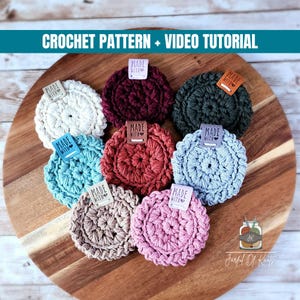 May include: A collection of eight round crochet coasters in white, dark red, dark green, turquoise, rust, light blue, beige, and pink. Each coaster features a small rectangular tag labeled "MADE WITH" and the text "CROCHET PATTERN + VIDEO TUTORIAL".