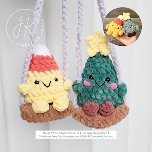 May include: Two plush, hanging ornaments: a candy corn and a Christmas tree. The candy corn is yellow with orange and white accents, and the tree is green with a yellow star. Both have smiling faces and are suspended by gray cords. The text reads: "This is NOT a full pattern; 2-in-1 Low Sew Candy Corn & Christmas Tree Plushie pattern is REQUIRED to work this mod."