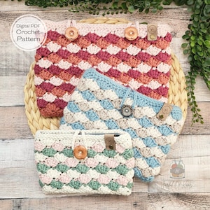 May include: Three crocheted cases in varying sizes and colors. The largest is a mix of pink, peach, and burgundy, the middle one is blue, gray, and white, and the smallest is green, pink, and white. Each case has a wooden button closure and the text "Digital PDF Crochet Pattern".
