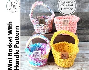 May include: Four crocheted mini baskets with handles. The baskets are in different colors: pink, yellow, blue and white, and beige. Each basket has a small brown leather tag that says "MADE WITH".