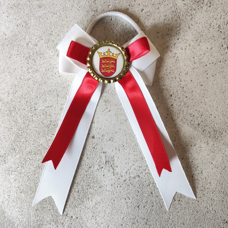 May include: A white and red bow with a gold and red crown emblem on a white background. The bow is tied with a white elastic band.