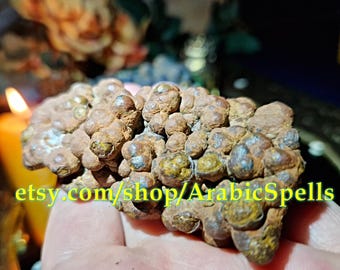 May include: A cluster of brown, spherical, and textured mineral formations with metallic, bronze-toned highlights. The surface is uneven and bumpy, featuring small, rounded nodules. The text etsy.com/shop/ArabicSpells is overlaid in yellow.