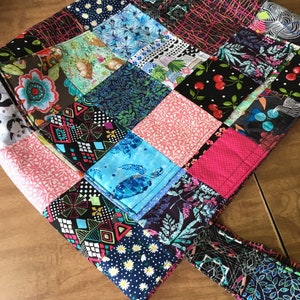 Peut inclure: Un sac fourre-tout en patchwork avec une vari&eacute;t&eacute; de tissus color&eacute;s. Le sac a un grand compartiment principal et une seule poign&eacute;e.