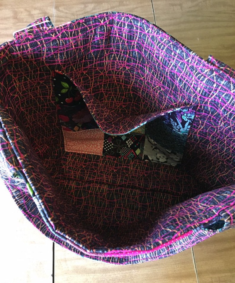 Peut inclure: L'int&eacute;rieur d'un sac cabas rose et noir avec un motif patchwork. Le sac est doubl&eacute; d'un tissu noir et blanc avec un motif rose et or.