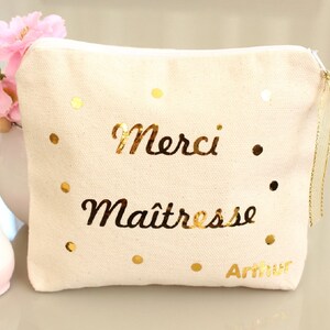 May include: A white canvas zippered pouch with gold glitter dots and the text "Merci Maitresse Arthur" in gold lettering.