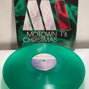 May include: A green vinyl record with a white label that says "Motown 1's Christmas" and lists the songs on the record. The record is in a plastic sleeve with a green and red cover that says "Motown 1's Christmas".