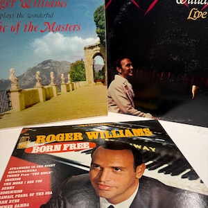 May include: Three vinyl record album covers featuring Roger Williams. One cover shows a stone terrace with statues, another shows Roger Williams live, and the third features a portrait of Roger Williams with the title Born Free and a track list.