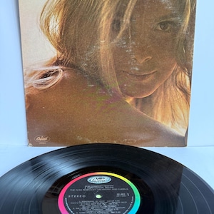 May include: A vinyl record and its square cardboard sleeve titled Romanoff Presents A Continental Affair. The sleeve features a portrait of a person with long hair. The black vinyl record has a central label with the Capitol Records logo.