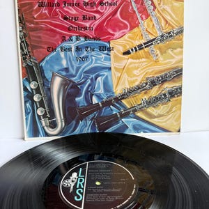 Pode incluir: Um disco de vinil de 1967 intitulado Remembering Willard Junior High School Stage Band Orchestra A & B Bands The Best In The West. A capa apresenta um saxofone, uma flauta e dois clarinetes sobre tecido drapeado vermelho, azul e amarelo.