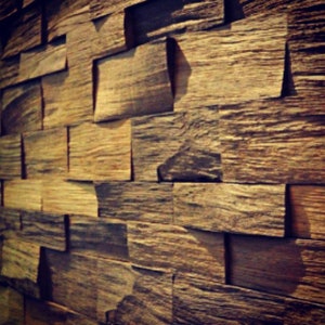 Könnte beinhalten: Eine Wand aus wiederverwendeten Holzdielen, jede mit einem einzigartigen Maserungsmuster und Farbabweichungen. Die Dielen sind in einem versetzten Muster angeordnet, was einen rustikalen und strukturierten Look erzeugt.
