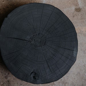 Peut inclure: Gros plan d'une tranche ronde de bois foncé avec des motifs de grain visibles. Le bois a une couleur foncée, presque noire.