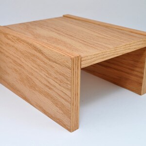 May include: A wooden riser with a natural finish. The riser is made of solid wood and has a simple, modern design. It is perfect for elevating objects, such as plants, books, or electronics.