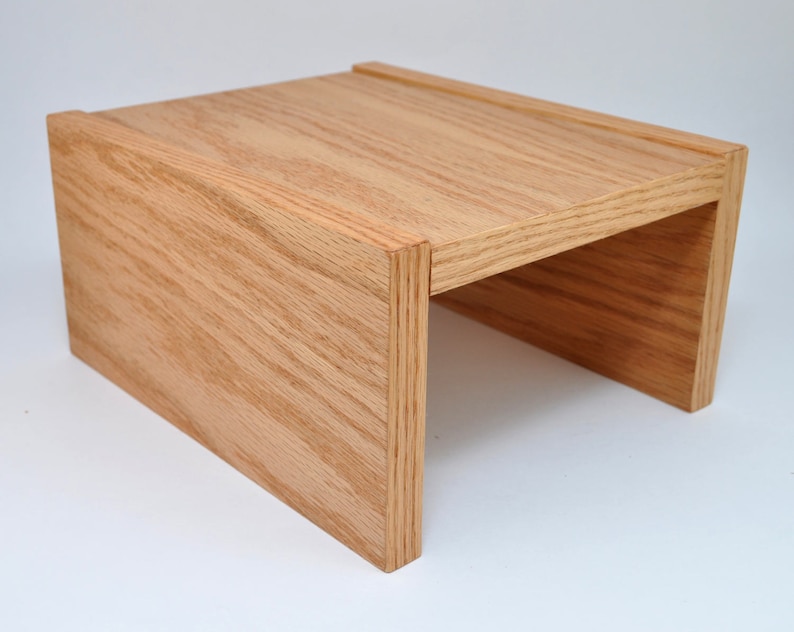 May include: A wooden riser with a natural finish. The riser is made of solid wood and has a simple, modern design. It is perfect for elevating objects, such as plants, books, or electronics.