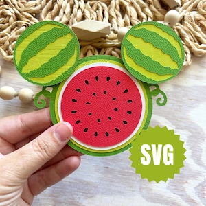 May include: A layered paper watermelon design with a red centre, green rind, and black seeds. Two smaller watermelon slices are above the main design. The word "SVG" is in a green starburst shape.