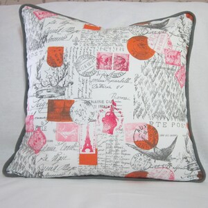 May include: A white cushion with a grey border features a vintage Parisian design with pink and orange stamps, handwritten script, and the Eiffel Tower. The text on the cushion reads "POSTA", "12.6 1824", "J. PARTEL", "Maua Huparbelle", "Veteria 21", "Roma", "NAIRE DU", "ZS145 TE FRANG", "ALT", "LE", "adame Caved", "a pie", "yend Mage", "Tour Eiff", "ATE", "AUERTE POST", "2200", "ONN", "cole est cxtu", "pir", "PO", "FONN", "12.00".