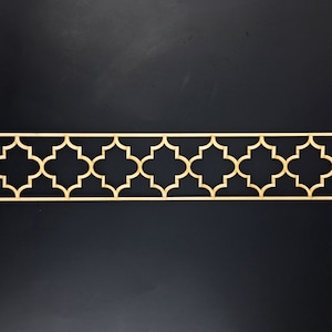 May include: A decorative wooden border with a repeating geometric pattern. The pattern is made up of four-pointed stars with rounded edges. The border is a light brown color and is set against a black background.
