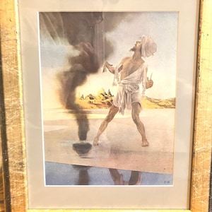 May include: A framed print of a man in a white robe standing in a desert landscape. He is looking up at a swirling cloud of smoke. The print is signed and dated "C.99".