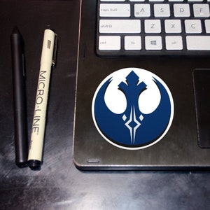 以下が含まれることがあります： 黒いノートパソコンに貼られた、青と白の反乱同盟軍のシンボルステッカー