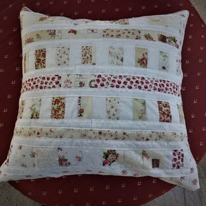 Puede incluir: Una almohada blanca con un diseño de patchwork con tela floral en tonos de rosa, verde y blanco. La almohada tiene un borde blanco y el texto "Jared" y "My Love" es visible en la parte delantera.