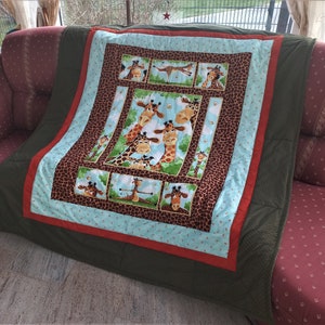 May include: A green, red, and blue patchwork quilt with a giraffe pattern. The quilt features multiple images of giraffes in various poses, including a group of three giraffes looking at each other.