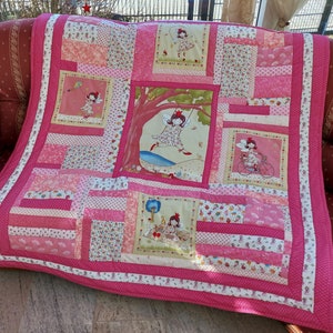 Könnte beinhalten: Eine rosafarbene und weiße Patchwork-Decke mit einem Blumenmuster und Bildern von Feen. Die Decke besteht aus verschiedenen Stoffen und hat einen rosa Rand.