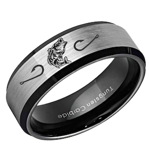 May include: A black and silver tungsten carbide ring with a brushed silver center band. The band features a detailed illustration of a fish and two fishing hooks. The inner band is black with the text "Tungsten Carbide".