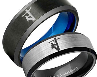 以下が含まれることがあります： 2つのタングステンカーバイドリング。1つは黒色で内側が青色、電線作業員のシルエット。もう1つは銀色で黒い縁取り、電線作業員のシルエット。リングには「Tungsten Carbide」の文字。