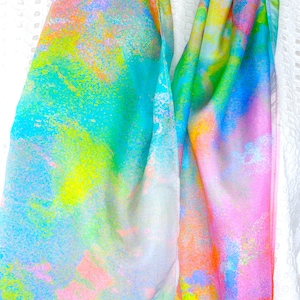 Op de afbeelding: Een kleurrijke zijden sjaal met een felblauw, groen, geel, roze en oranje abstract patroon.