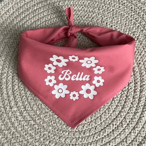May include: A pink bandana with white flowers and the name "Bella" printed on it.