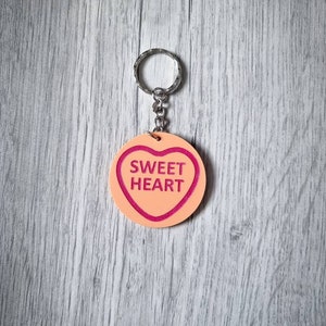 May include: A pink heart-shaped keychain with the words "SWEET HEART" in pink lettering.