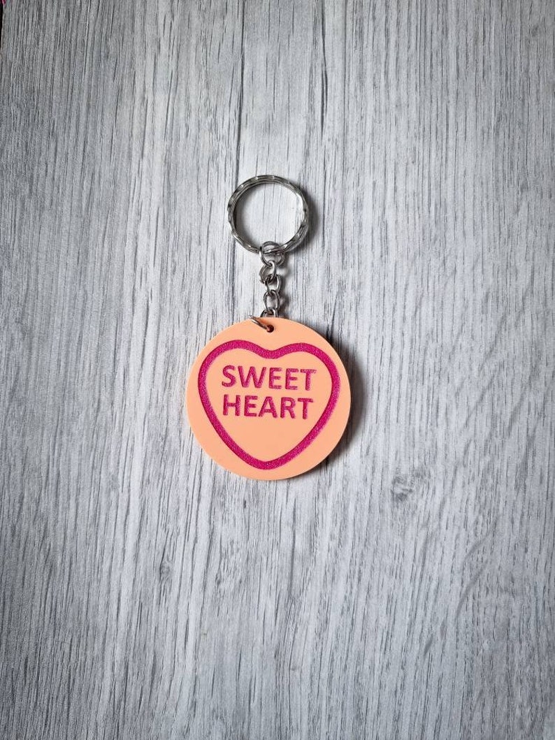 May include: A pink heart-shaped keychain with the words "SWEET HEART" in pink lettering.