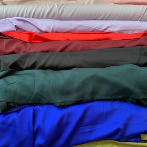 May include: A stack of fabric swatches in various colors, including white, beige, pink, lavender, red, burgundy, black, green, blue, and yellow.
