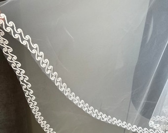 May include: White bridal veil with a scalloped edge. The veil is made of soft tulle and has a delicate, romantic look.