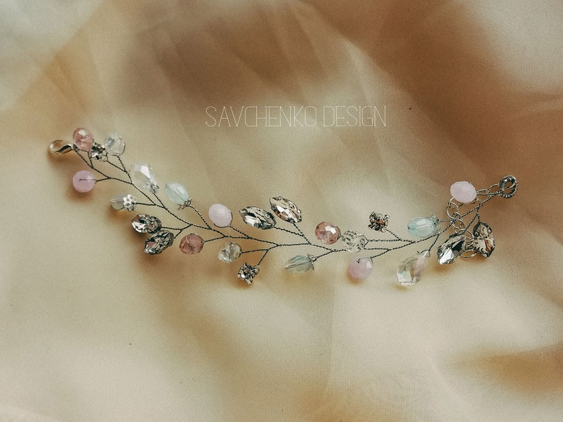 May include: A delicate silver wire hair vine with pink and blue beads and crystals. SAVCHENKO DESIGN is written in the background.