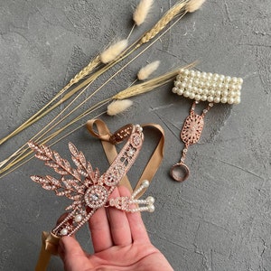 May include: A set of two gold-toned headbands with pearl and crystal embellishments. One headband is a delicate chain with a floral design and the other is a simple band with pearls.