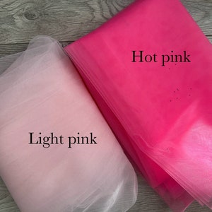 May include: Two pieces of tulle fabric, one light pink and one hot pink. The fabric is soft and sheer, and it is perfect for crafting or decorating.