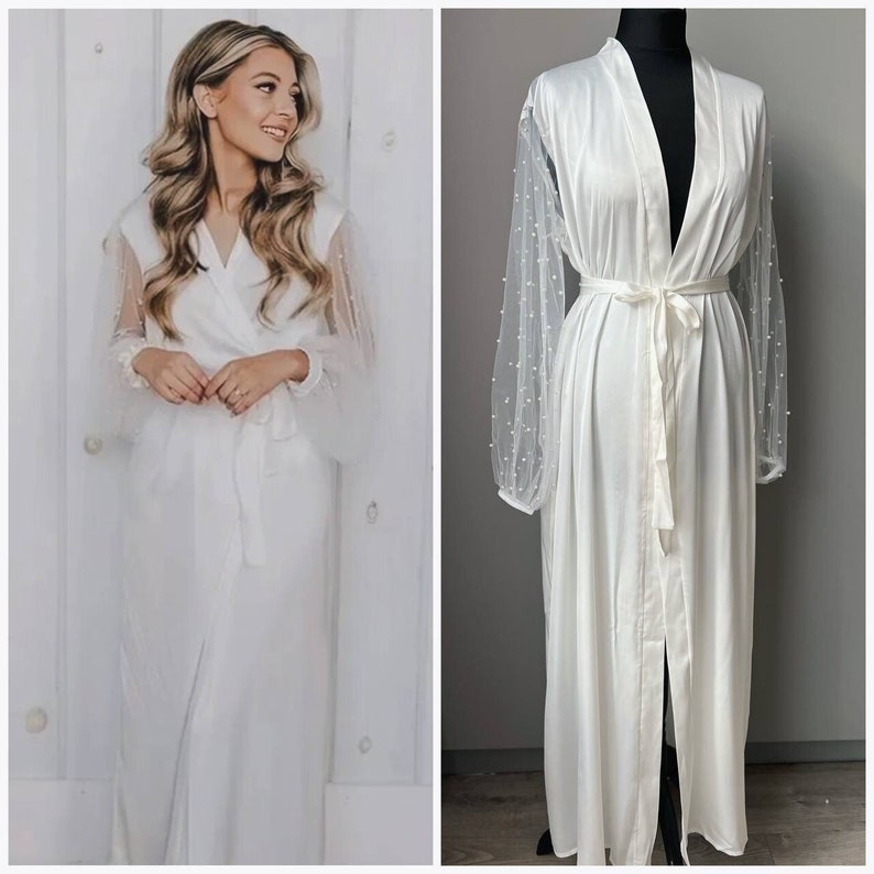 May include: White satin robe with long sleeves and a pearl-embellished mesh overlay. The robe has a V-neckline and a tie belt.
