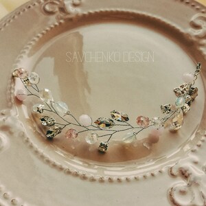 May include: A delicate silver wire hair comb with pink and clear glass beads and crystals. The comb is shaped like a branch with leaves and flowers.