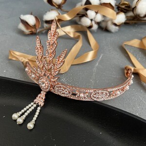 May include: A rose gold headband with a delicate pearl and crystal design. The headband features a leaf motif and a dangling pearl tassel.