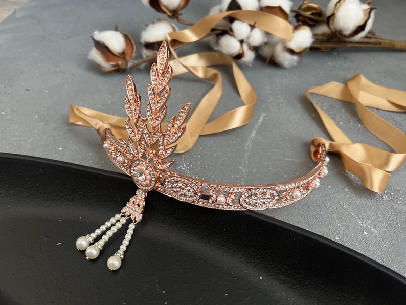 May include: A rose gold headband with a delicate pearl and crystal design. The headband features a leaf motif and a dangling pearl tassel.