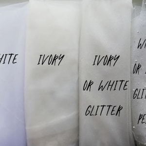May include: Four swatches of tulle fabric in white and ivory. The swatches are labeled with the colors and options for glitter or pearls.
