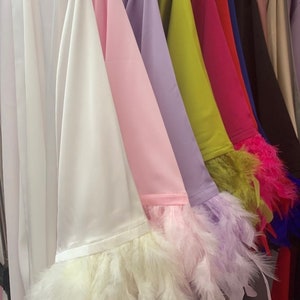 May include: A row of satin robes with feather trim on the sleeves. The robes are in various colors, including white, pink, lavender, green, red, blue, black, and beige.