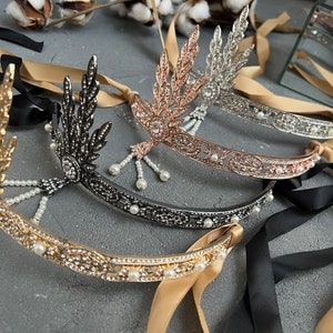 May include: Four gold, silver, black, and rose gold headbands with pearl accents and leaf designs. The headbands are tied with black and beige ribbons.